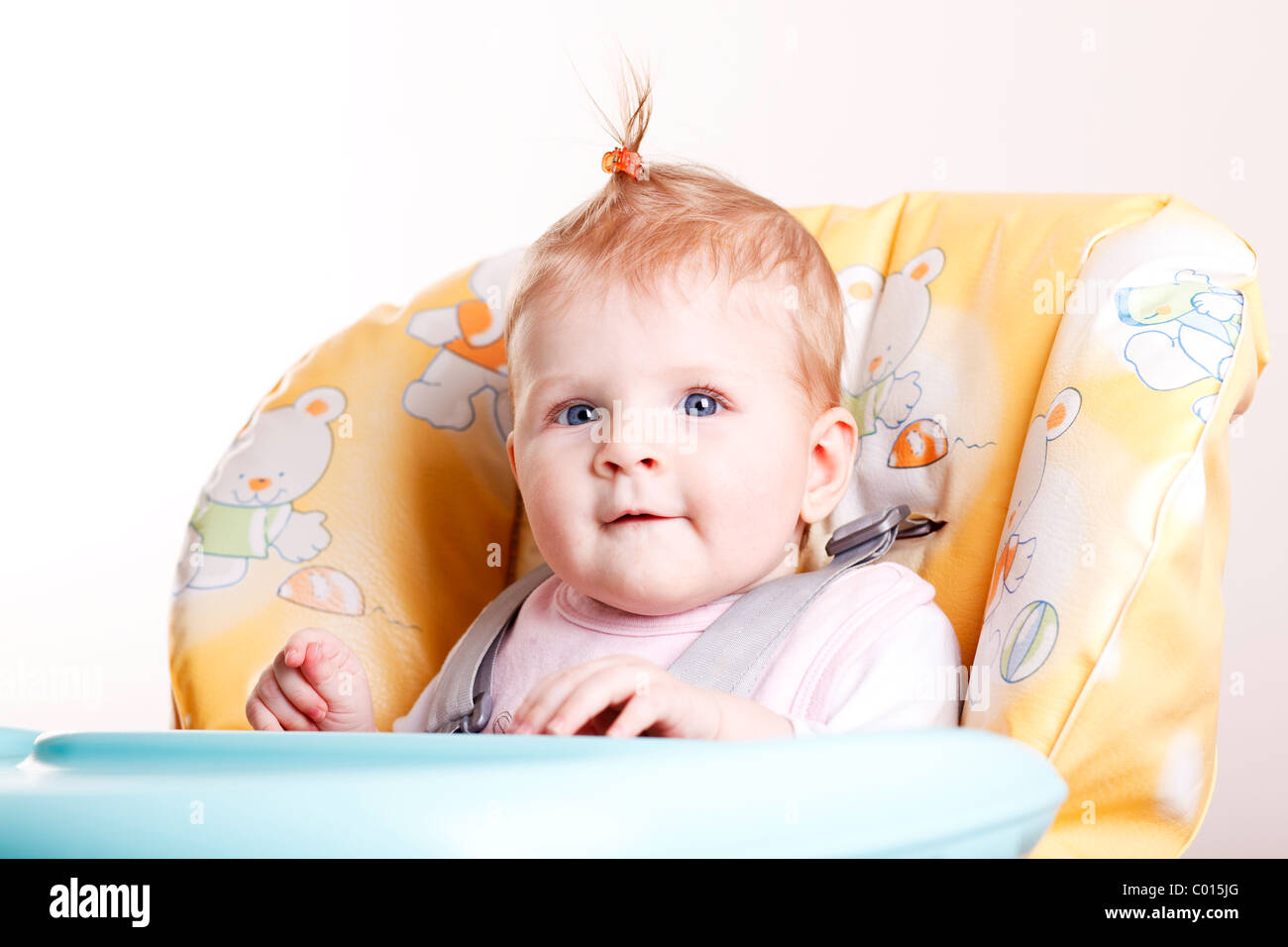 Baby Girl avec des tournants assis sur la chaise haute. Banque D'Images