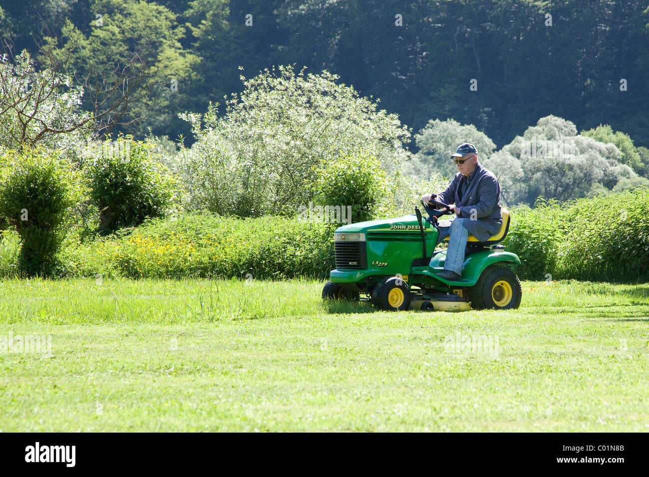 Homme âgé de tondre la pelouse sur un John Deere tondeuse à siège, Bengel, Rhénanie-Palatinat, Allemagne, Europe Banque D'Images Homme âgé de tondre la pelouse sur un John Deere tondeuse à siège, Bengel, Rhénanie-Palatinat, Allemagne, Europe Banque D'Images