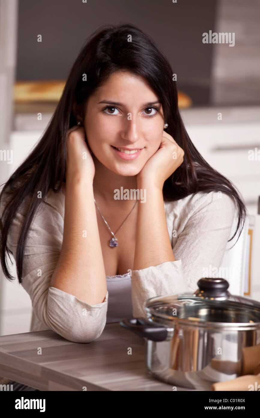 Jeune femme assise à une table à manger dans la cuisine, sac de papier contenant des achats effectués à l'avant Banque D'Images