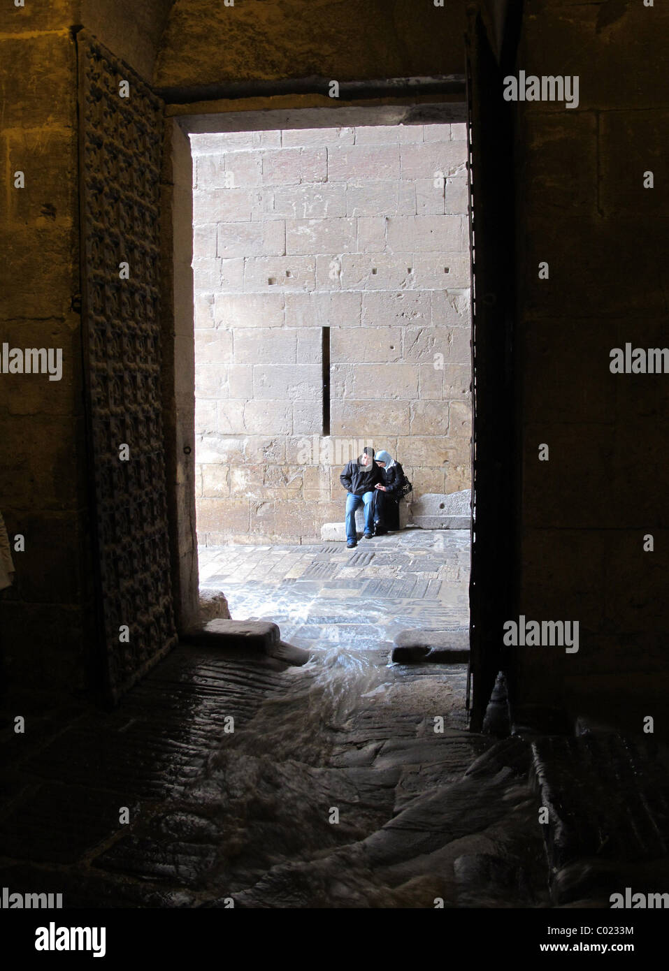 L'entrée principale de la citadelle de l'Aleppo Syrie avec l'eau de pluie passé en courant un homme et femme à l'abri de la pluie Banque D'Images