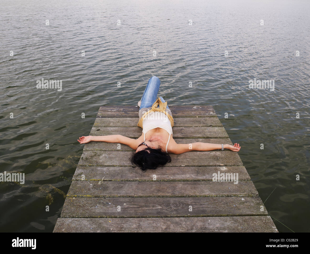 Woman lying on a jetée en bois sur un lac, plateau des lacs Mecklembourgeois, Mecklembourg-Poméranie-Occidentale, Allemagne, Europe Banque D'Images