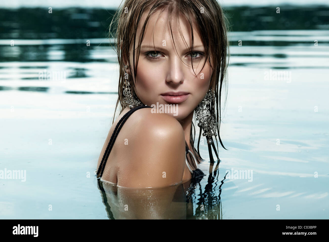 Jeune femme dans un maillot noir et avec les cheveux mouillés, la baignade dans un lac Banque D'Images