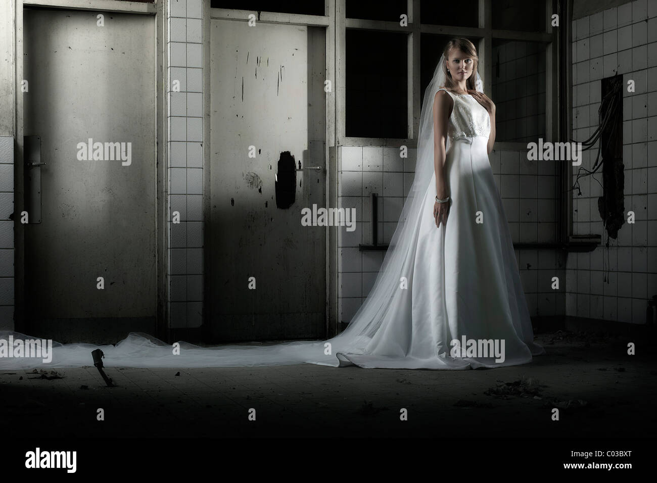 Jeune femme en robe de mariée avec voile dans un emplacement urbain Banque D'Images