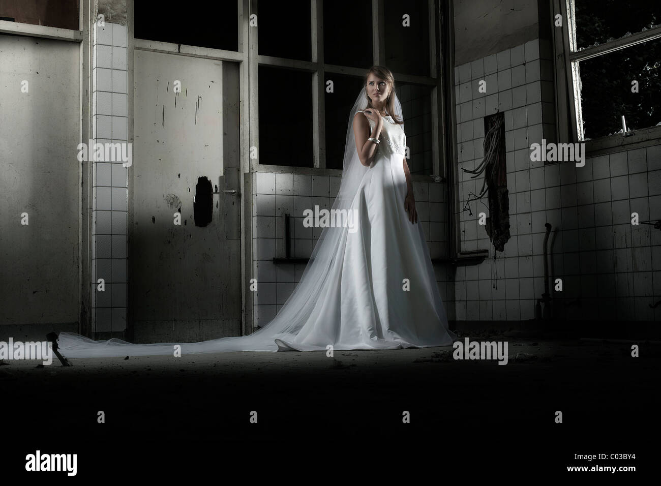 Jeune femme en robe de mariée avec voile dans un emplacement urbain Banque D'Images