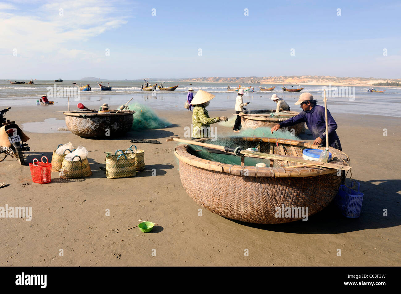 Avec les pêcheurs, les coracles ronde typiques bateaux de pêche sur la plage de Mui Ne sur la mer de Chine du Sud, Vietnam du Sud Banque D'Images