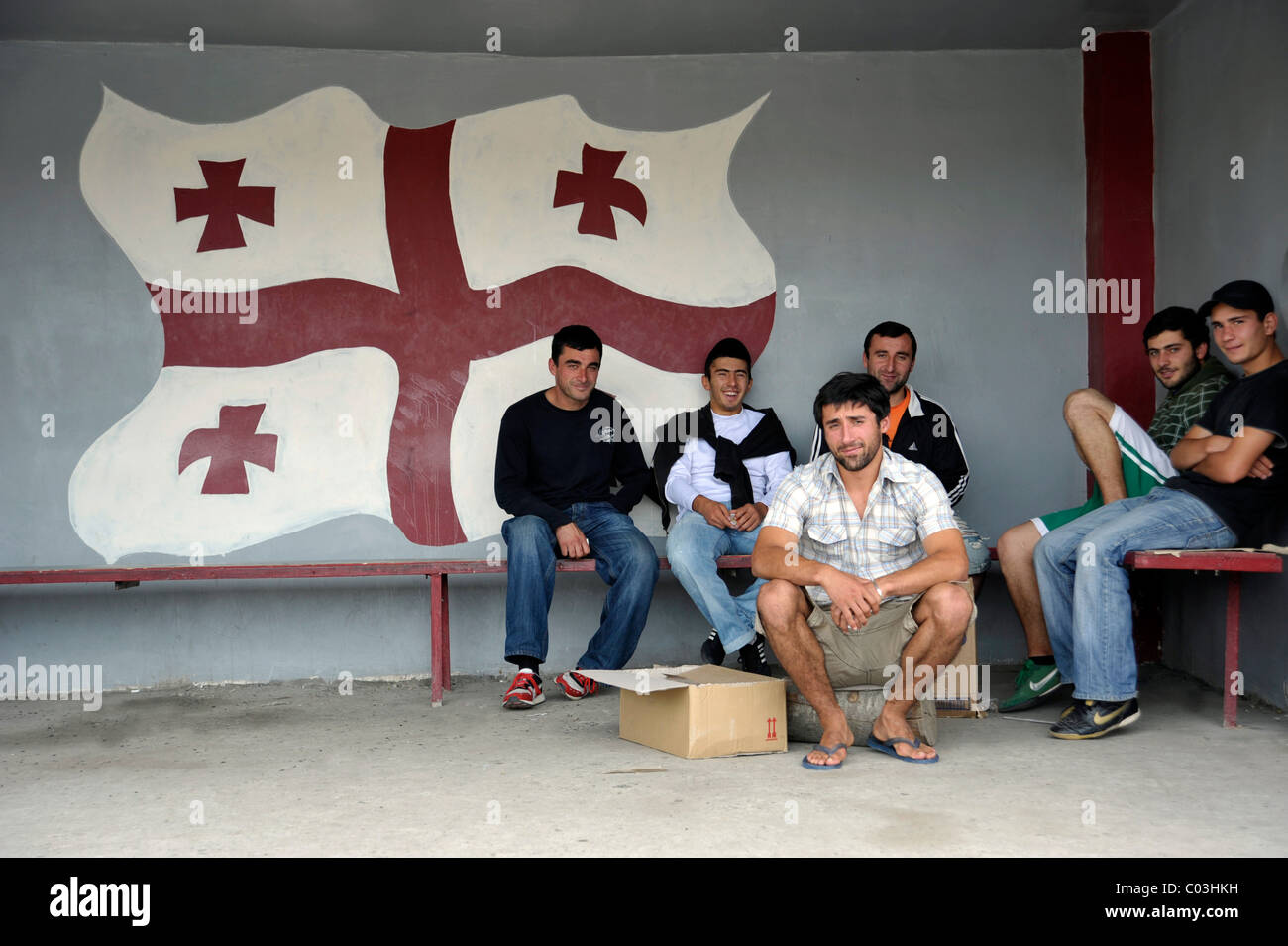 Les jeunes hommes en face de l'indicateur de la Géorgie à un arrêt d'autobus, d'Akhalkalaki, Shida Kartli, la Géorgie, l'Asie occidentale Banque D'Images