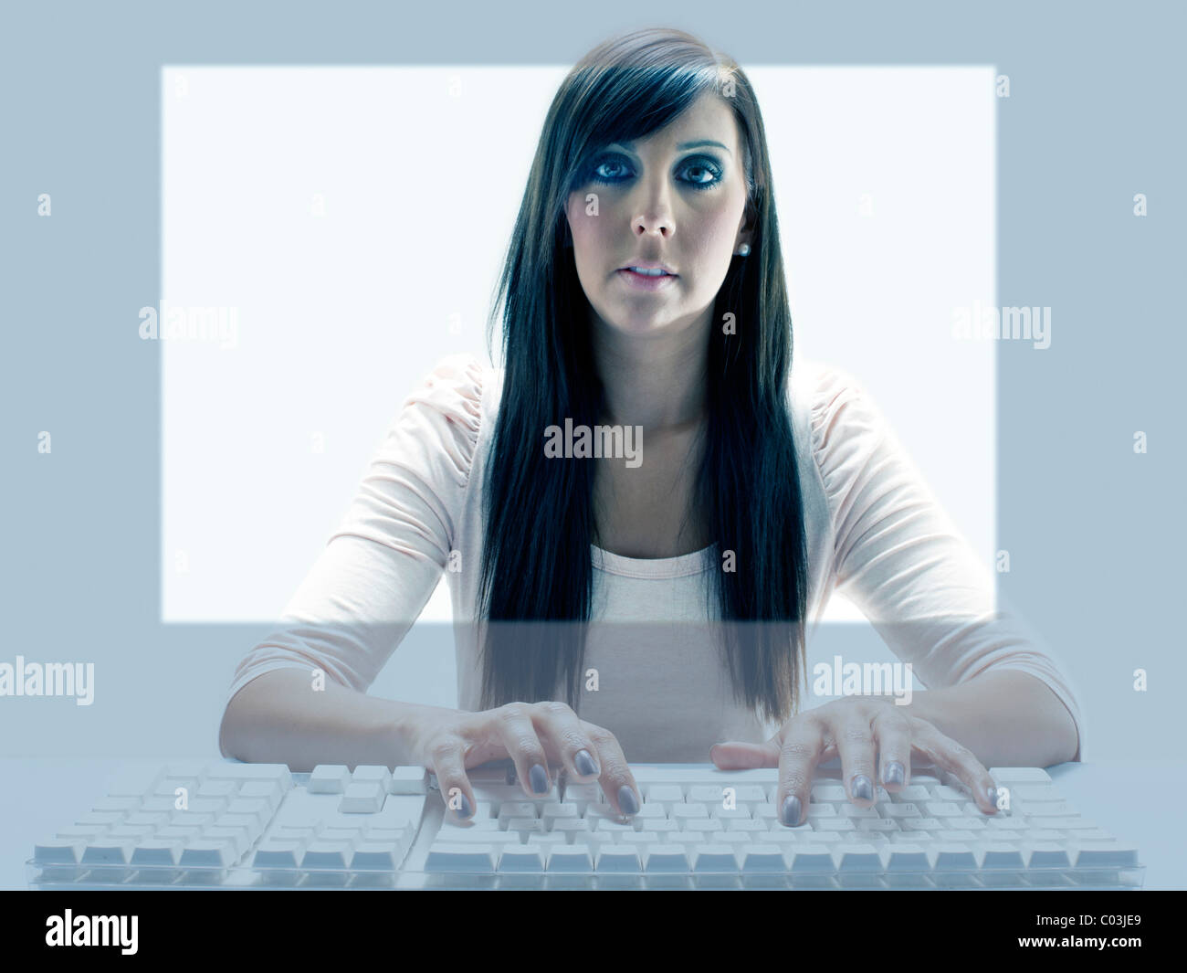 Jeune femme vue à travers l'écran d'un ordinateur tout en utilisant le clavier Banque D'Images