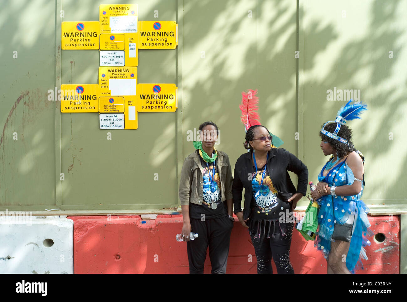 Les femmes déguisés pour le carnaval debout à côté d'un trafic minimal, le carnaval de Notting Hill, Londres Banque D'Images