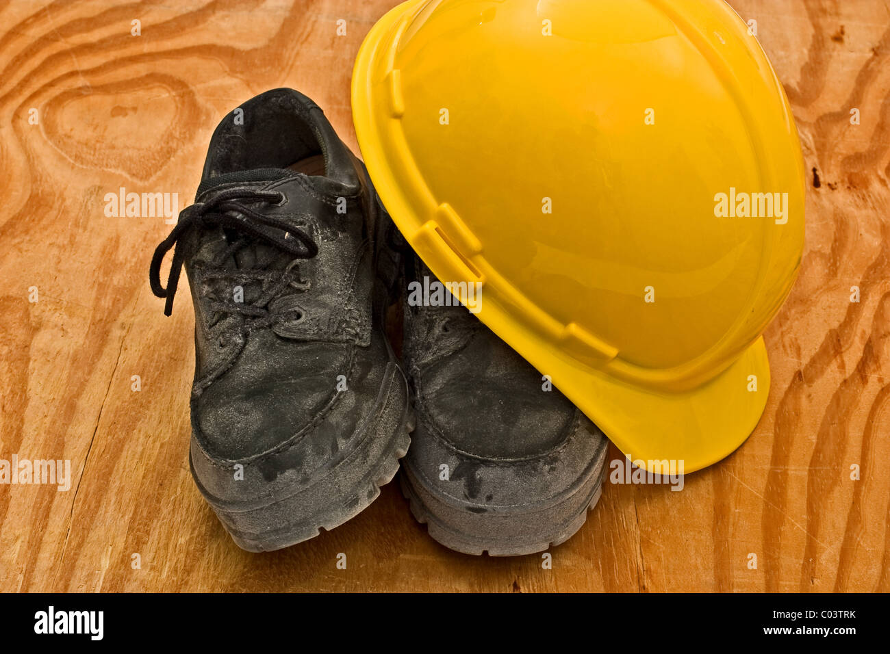 Casque jaune sur le dessus d'une paire de chaussures de travail sale épais Banque D'Images