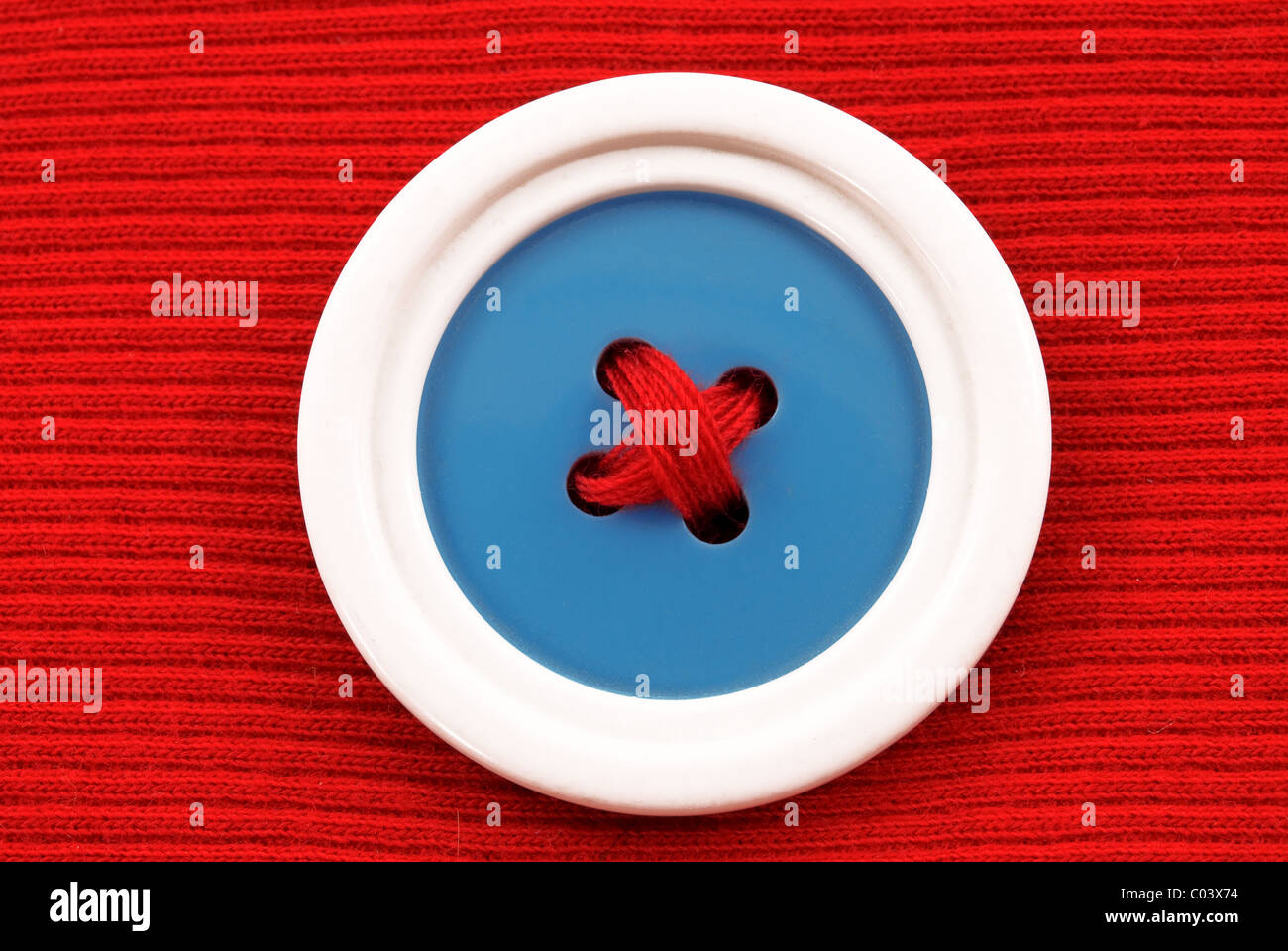 Bouton bleu avec bordure blanche sur un fond rouge Banque D'Images