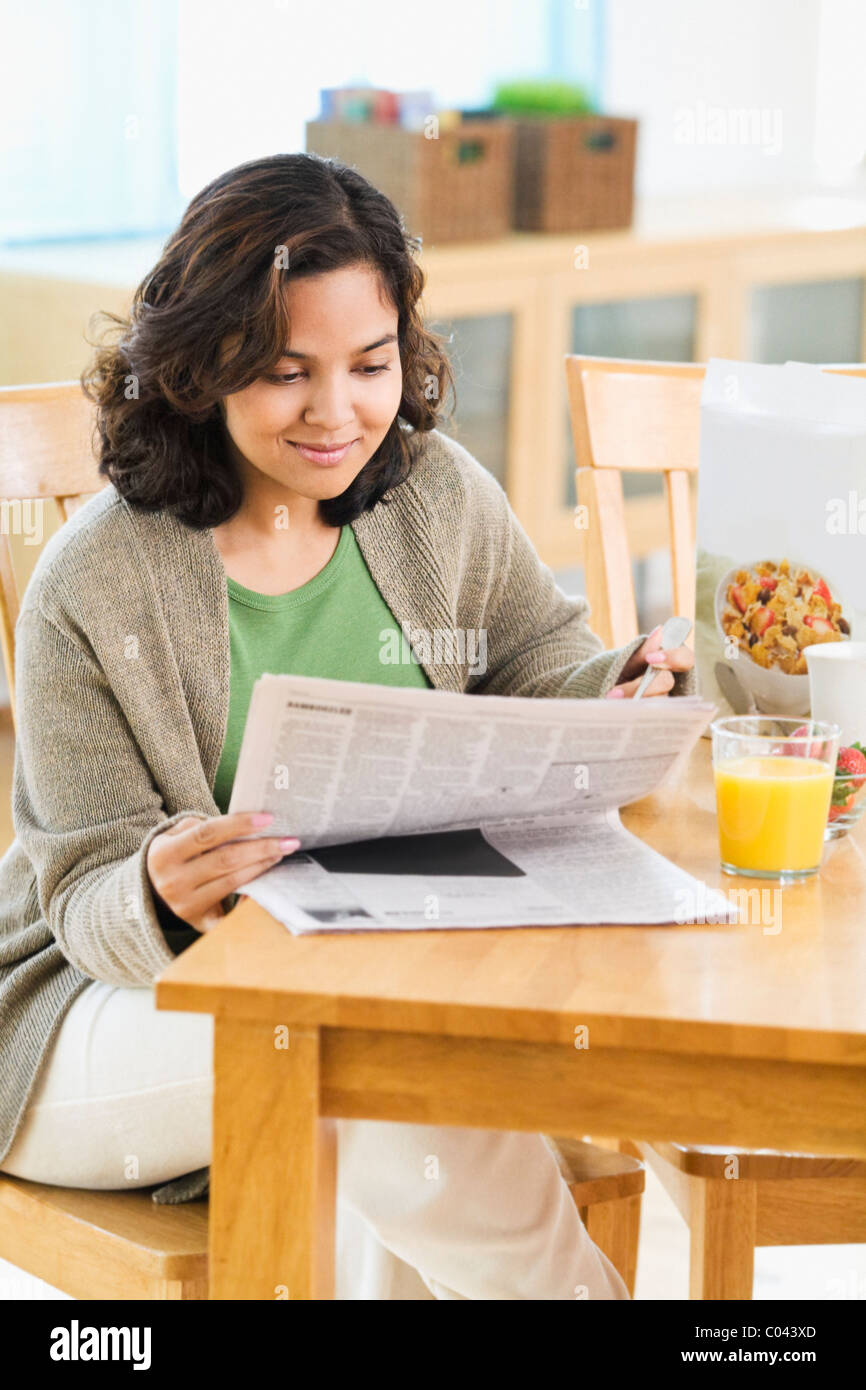 Femme lisant le journal et prendre le petit-déjeuner Banque D'Images