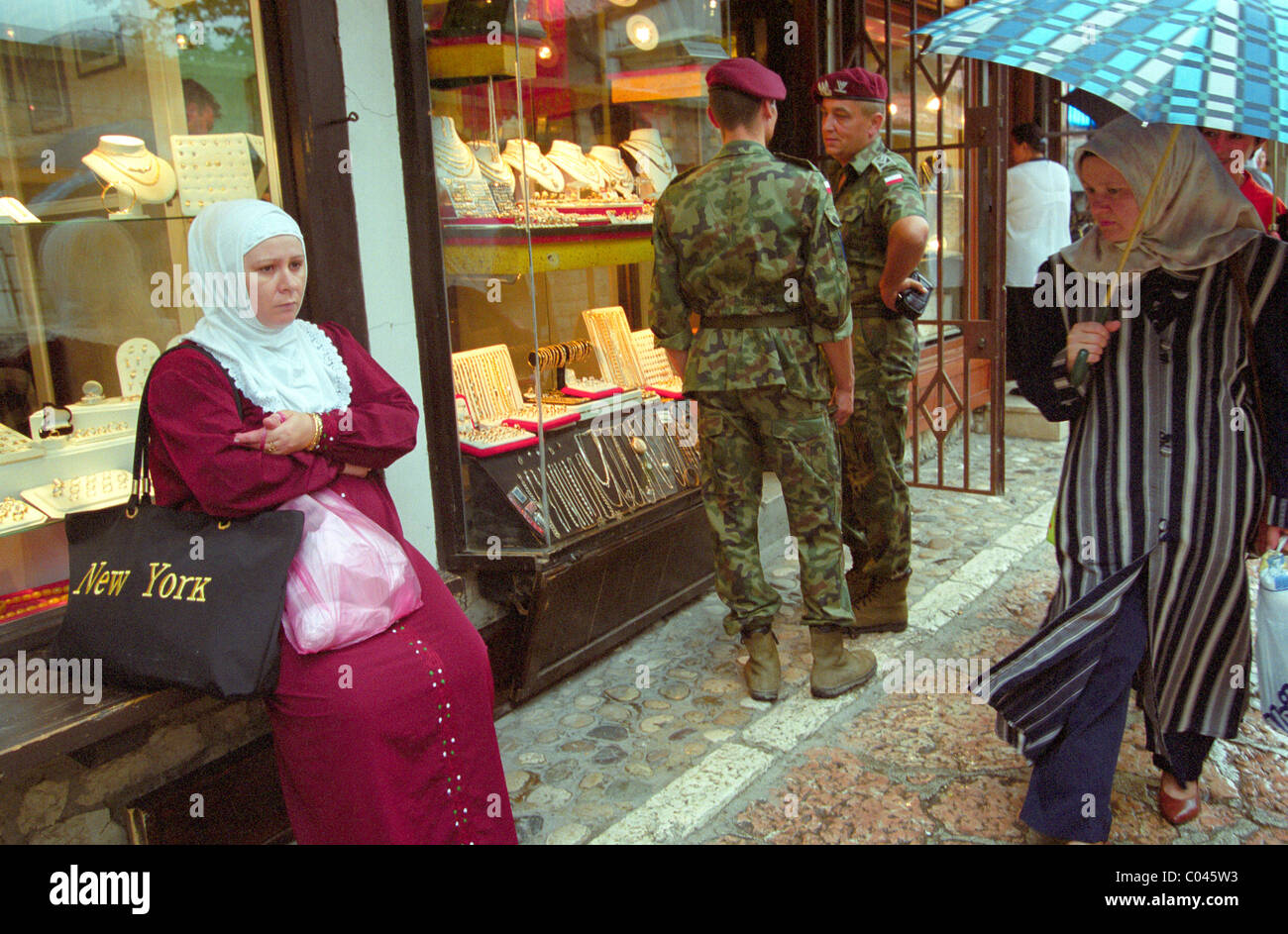 Une femme musulmane dans la vieille ville de Sarajevo comme deux casques bleus des Nations Unies se trouvent à proximité de parler Banque D'Images