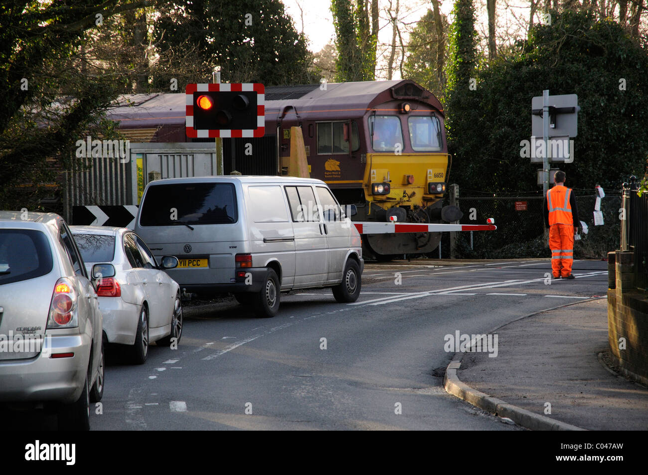 Employé de chemin de fer à des vêtements de sécurité réfléchissant à une seule barrière de passage à niveau près de Petersfield Hampshire England UK Banque D'Images