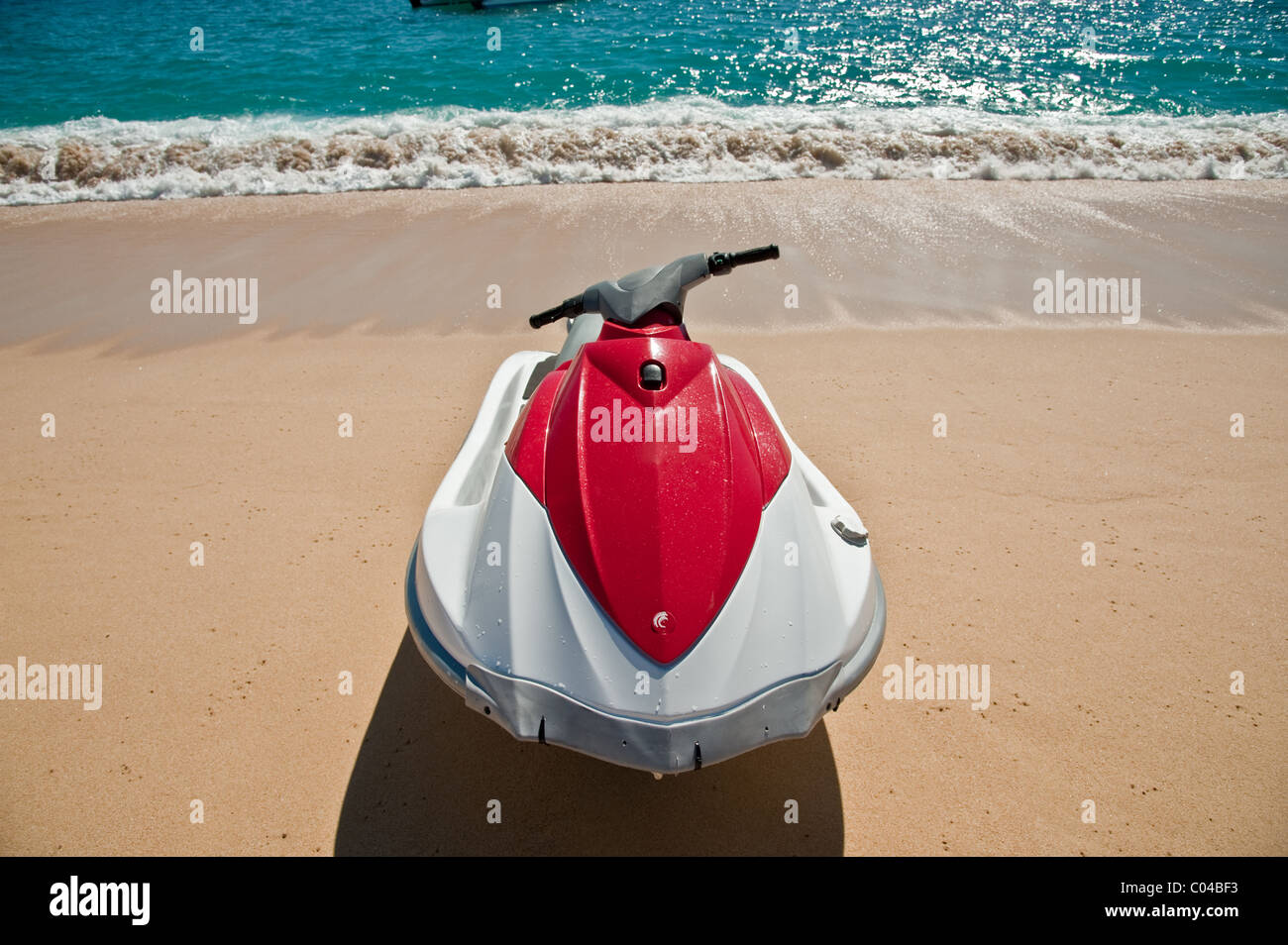 Un jet ski de l'eau placé sur une plage de sable avec des vagues douces  jusqu'écrasement derrière elle Photo Stock - Alamy
