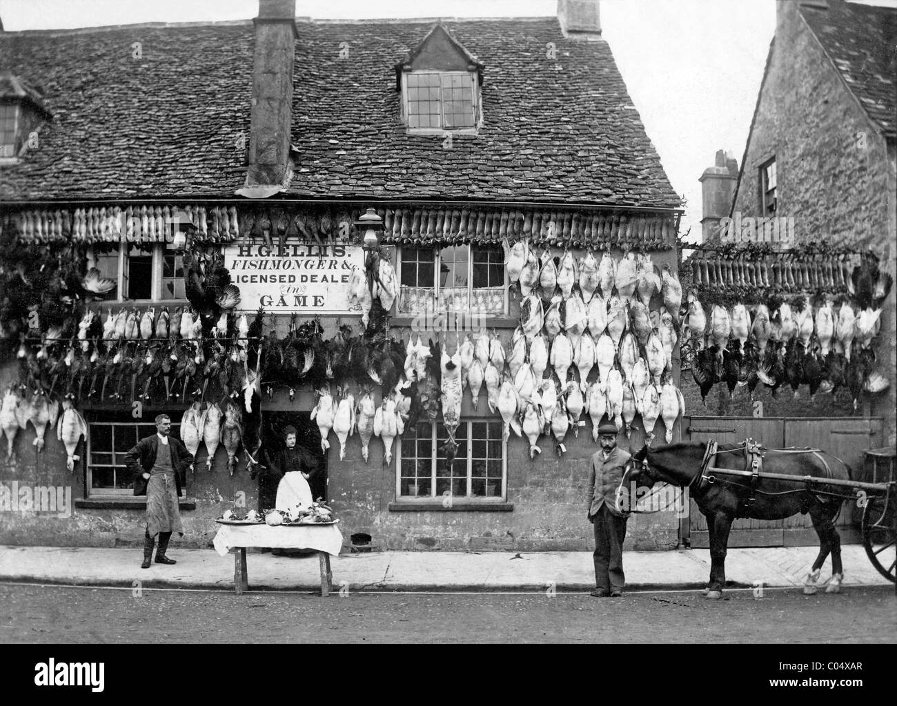 Commerçant rural vendant des oiseaux de gibier, des canards, des lapins d'oies de Cottage Shop, boucher ou donneur de gibier, Lincolnshire, Angleterre c1900 Vintage ou Old photo ou photo Banque D'Images