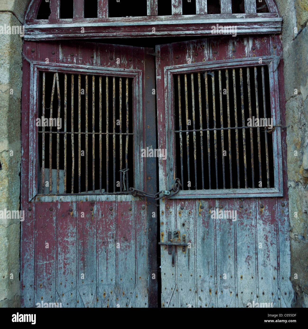 Portes rustiques en bois avec des barres métalliques dans un vieux bâtiment en pierre situé dans un village abandonné pendant l'heure d'or Banque D'Images