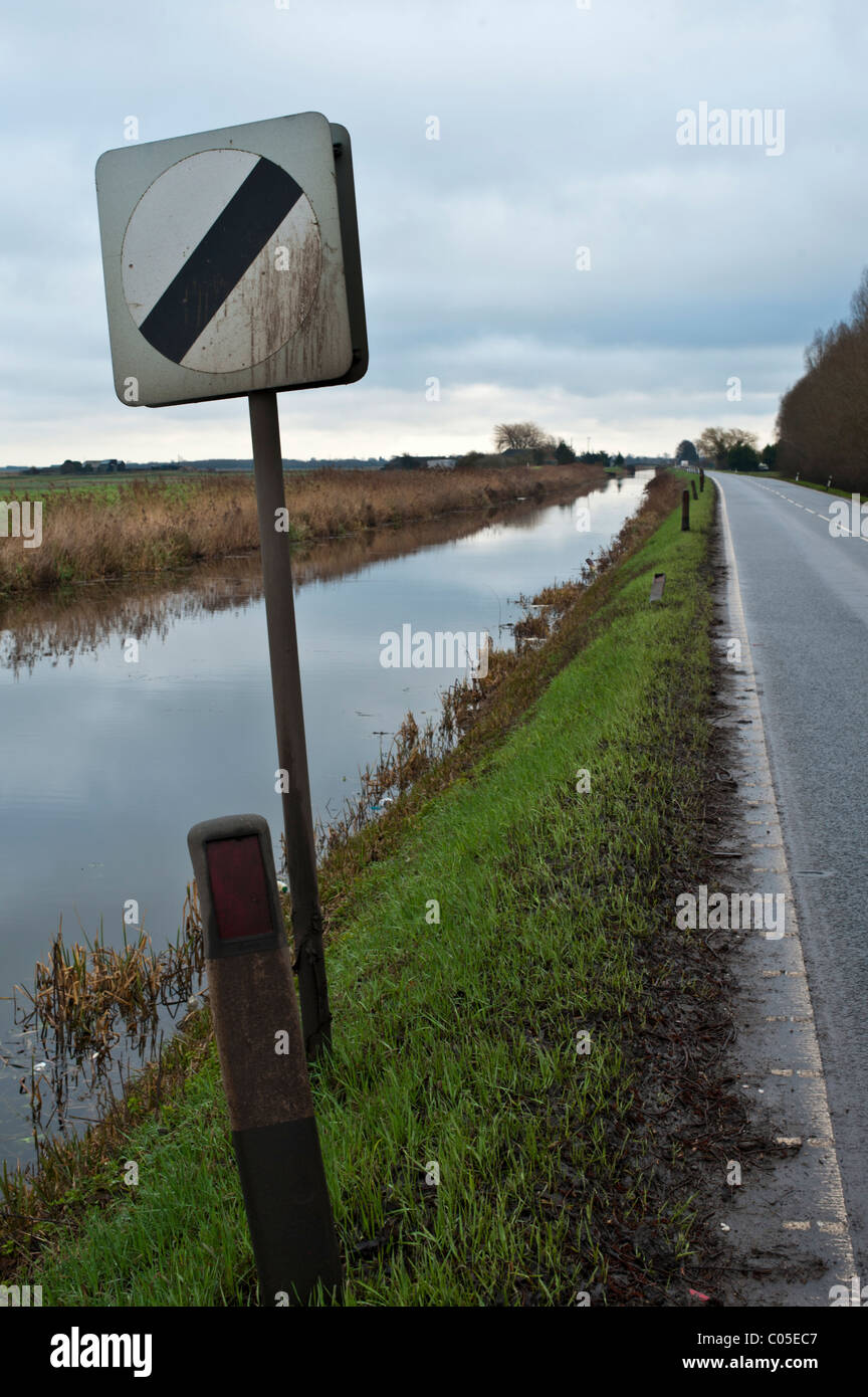 Les panneaux de limite de vitesse sur la route qui longe une Fenland drain. Pas de barrières, la cause de certains accidents désagréables si l'excès de vitesse. Banque D'Images