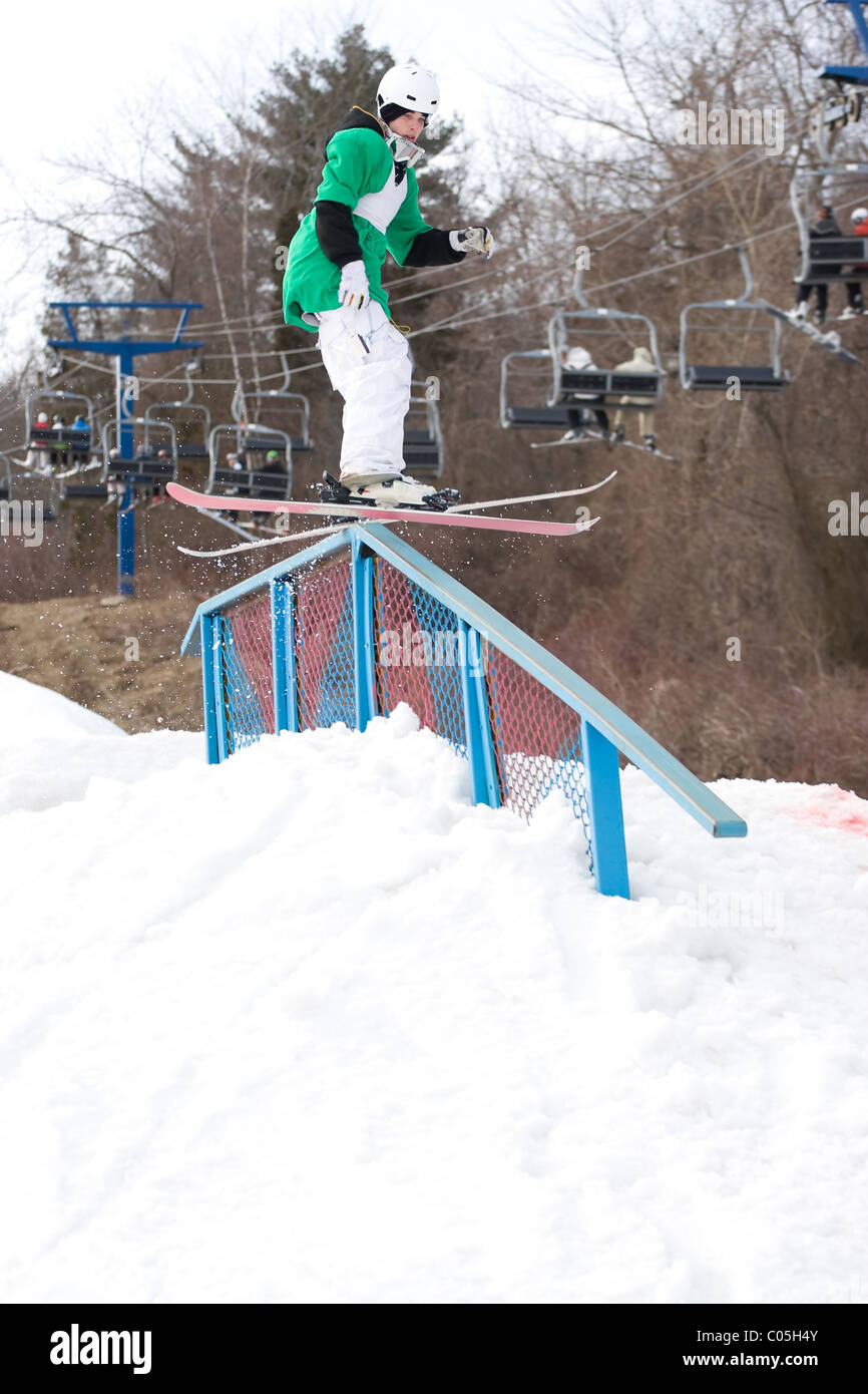 Un jeune skieur freestyle meuler la une rampe sur ses skis. Banque D'Images