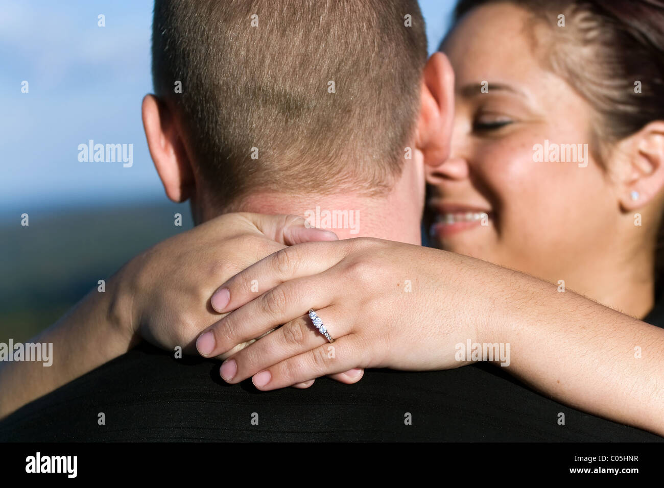 Un jeune couple qui vient de s'engagé. Profondeur de champ avec l'accent sur la bague de fiançailles en diamants. Banque D'Images