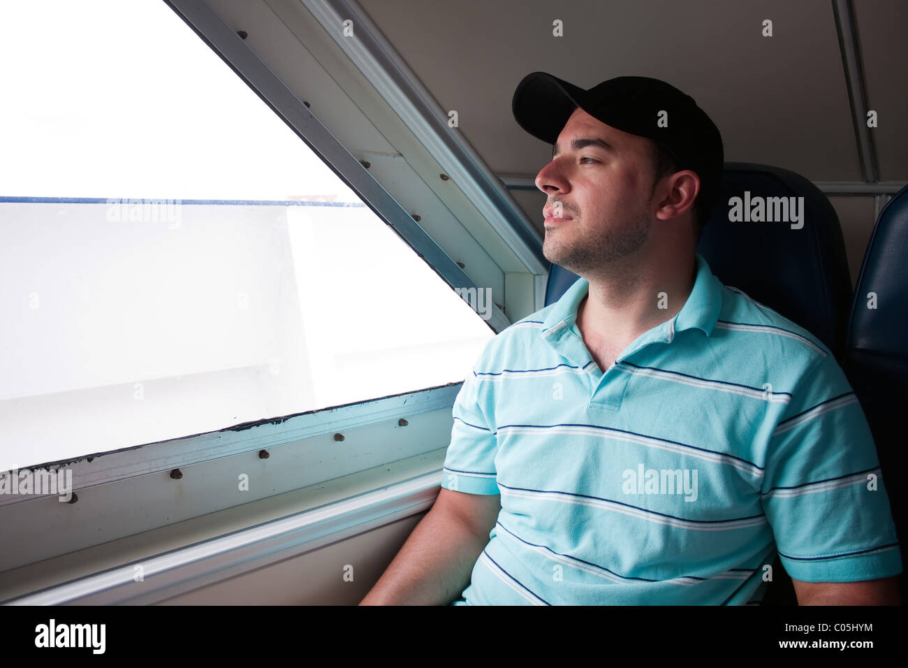 Une fatigue à passager assis sur un ferry regarde par la fenêtre comme il attend l'arrivée à sa destination. Banque D'Images