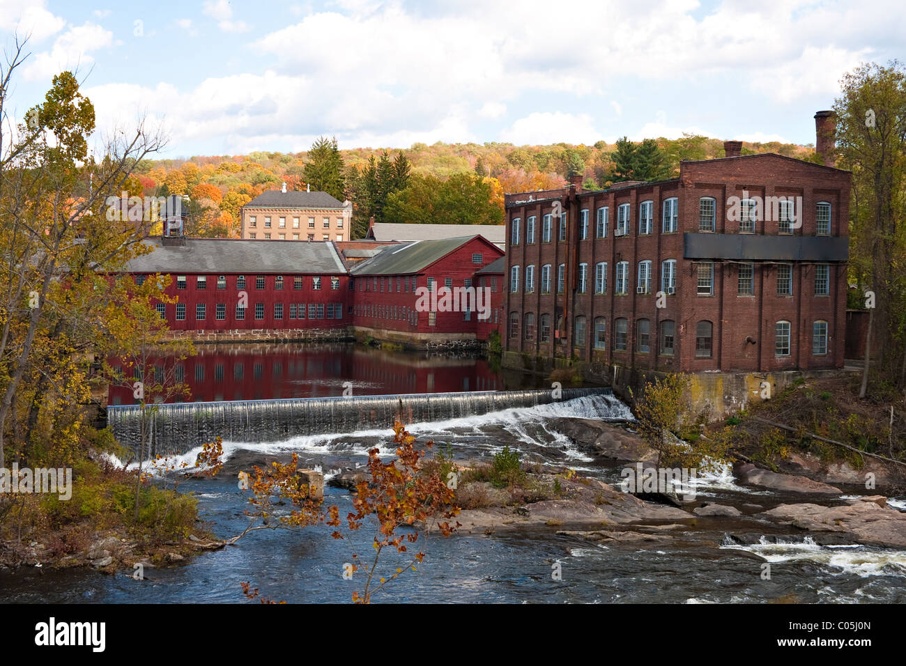 Un automne rivière scène avec quelques chutes et ancien moulin à côté de bâtiments avec feuillage coloré à l'horizon. Banque D'Images