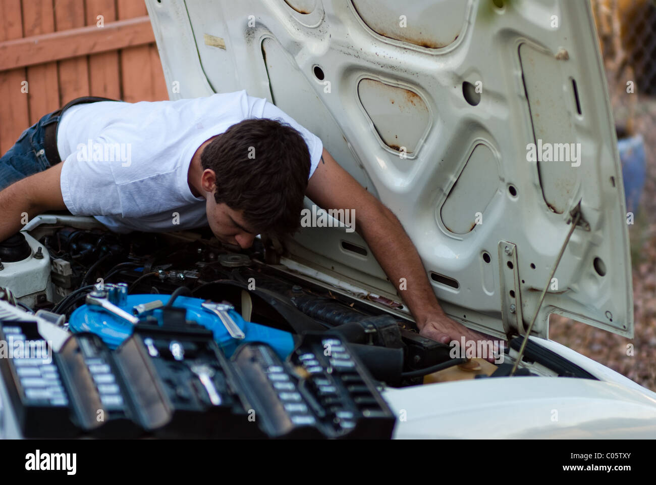 Man working on car en cour. Faire vous-même l'exécution de la réparation automobile mécanique. L'examen de compartiment moteur pour signes de difficultés. Banque D'Images