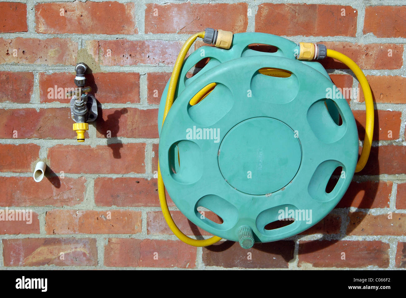 Un robinet extérieur, avec le raccord de flexible, et d'un enrouleur de tuyau, sur le mur de brique d'une maison britannique. Il y a une citerne tuyau de trop-plein aussi. Banque D'Images