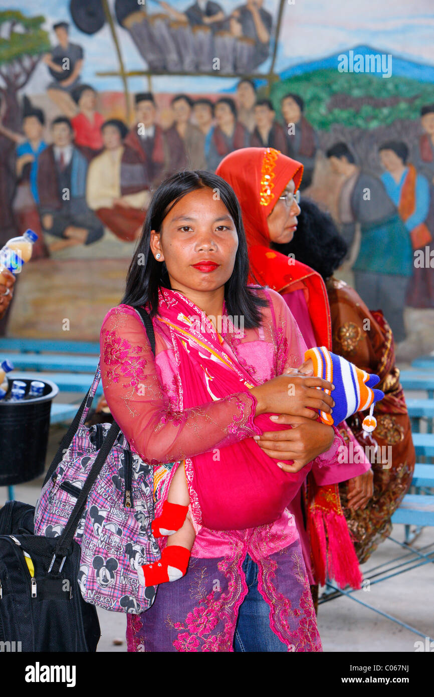 La mère et l'enfant dans une écharpe porte-bébé, des invités lors d'une cérémonie de mariage, Siantar, région de Batak, Sumatra, Indonésie, Asie Banque D'Images