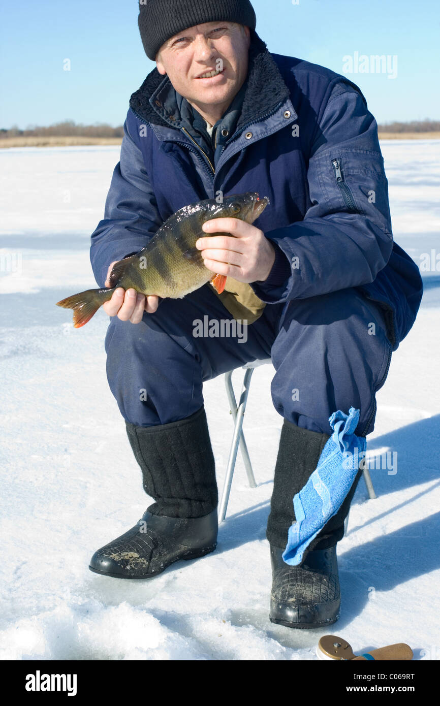 Pêcheur a caughted grande perche sur la pêche d'hiver Banque D'Images