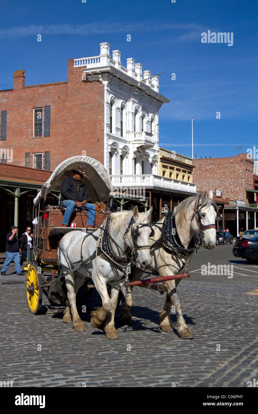 Les touristes voyager dans un wagon couvert à chevaux à Old Sacramento State Historic Park à Sacramento, Californie, USA. Banque D'Images