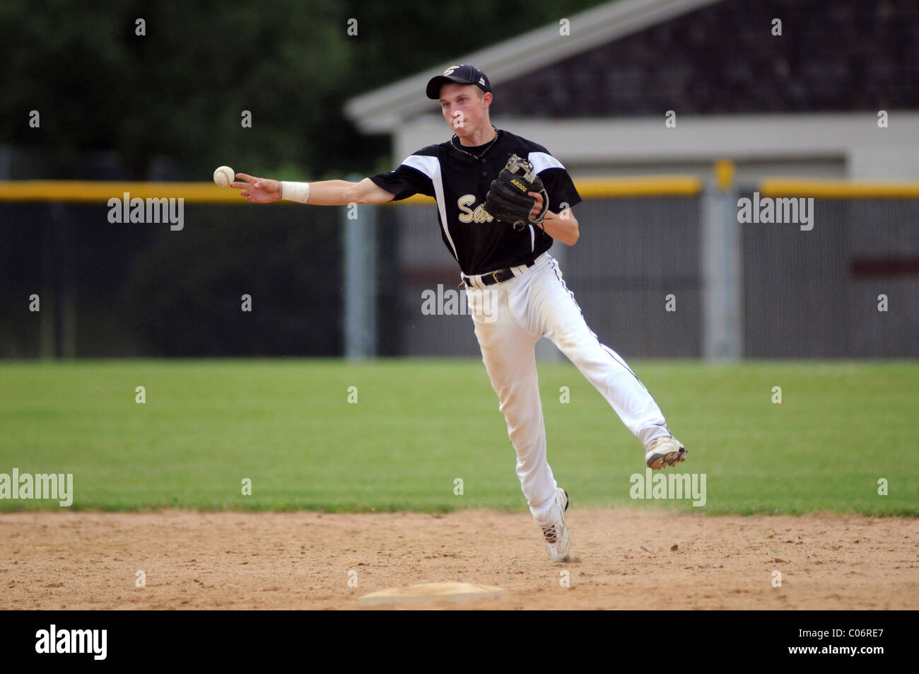 L'arrêt-court d'un match de baseball de l'école secondaire la libération d'un lancer au premier but. USA. Banque D'Images