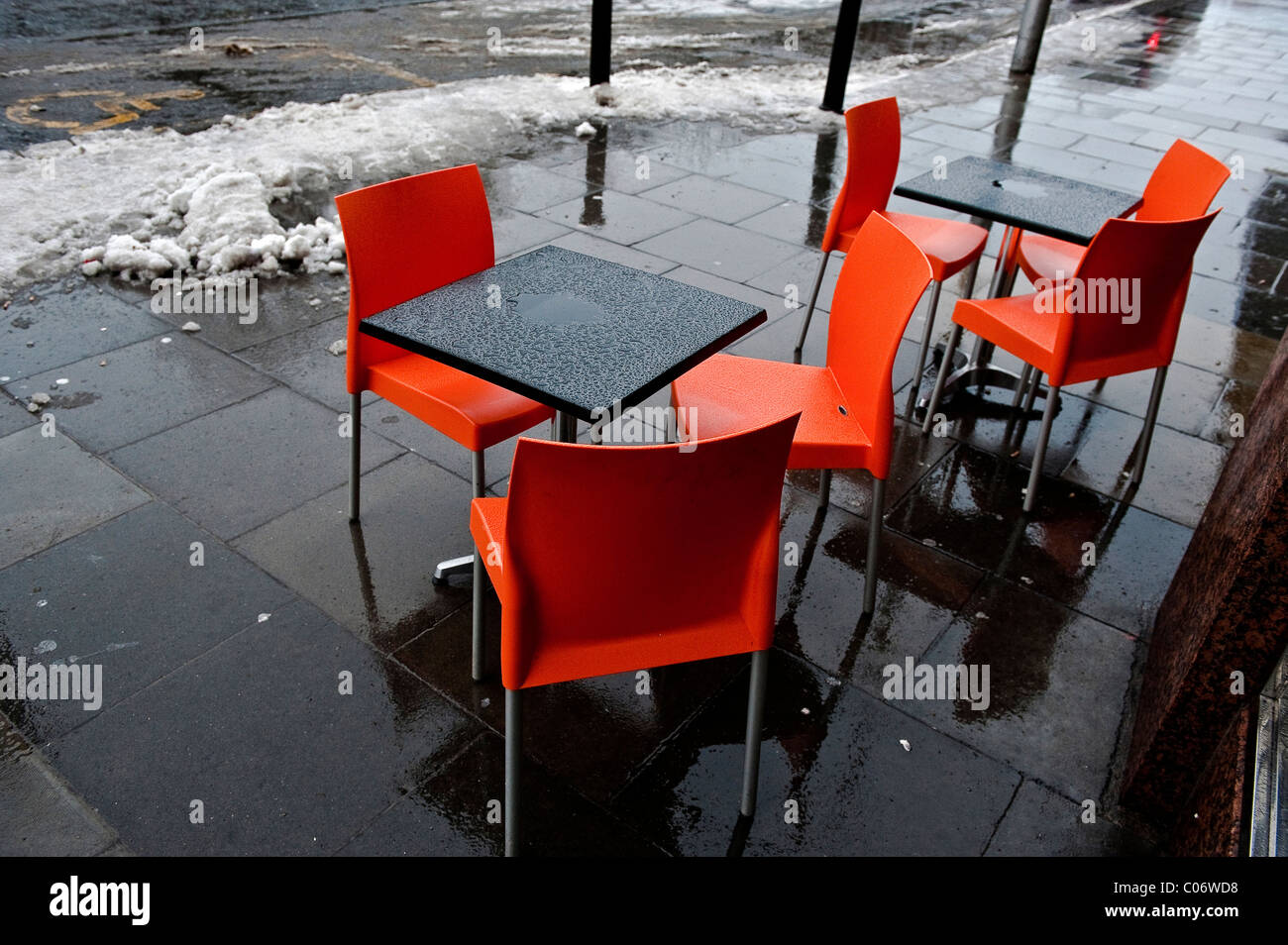 La fonte de la neige à côté de tables et chaises orange extérieur d'un café sur un début de l'hiver matin sur St Stephen's Green, Dublin en Irlande. Banque D'Images