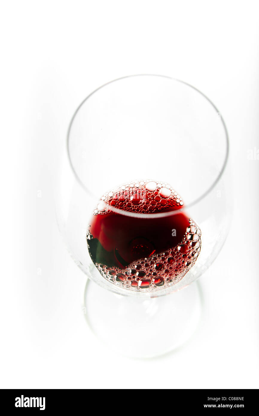 Un verre de vin rouge est versé à partir de la bouteille sur un fond blanc. Banque D'Images