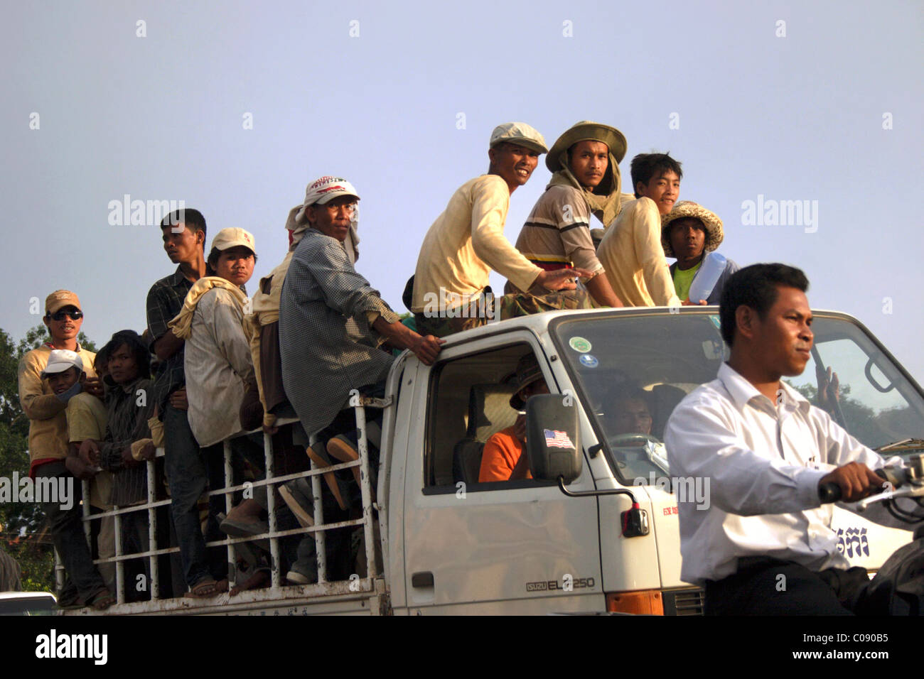 Un groupe de travailleurs de sexe masculin sont équitation dans un plein camion à plateau 250 Isuzu ELF près du fleuve Mékong à Phnom Penh, Cambodge. Banque D'Images
