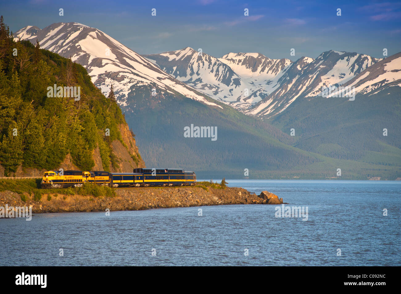 Un train de voyageurs Alaska Railroad arrondit un corner le long du ruisseau d'oiseaux près de Turnagain Arm, Southcentral Alaska, l'été Banque D'Images