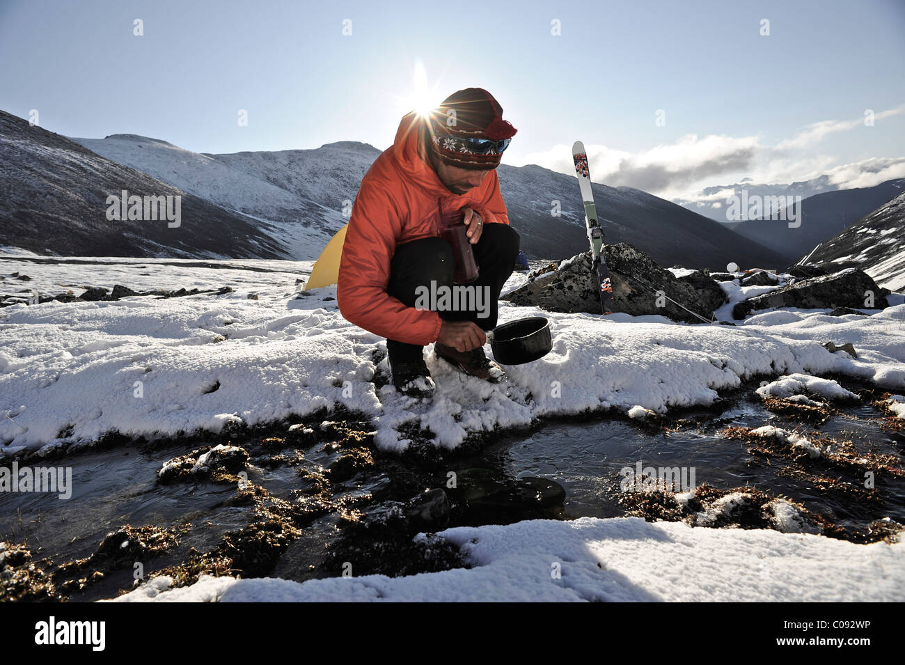 Pan se remplit avec de l'eau Backpacker dans un ruisseau à un camp alpin Mt ci-dessous. Chamberlin, Brooks, RFNA, Arctic Alaska, l'été Banque D'Images