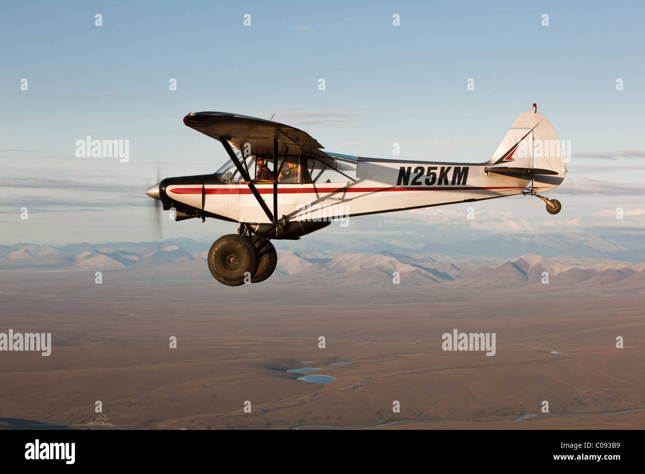 Vue aérienne d'un Piper Super Cub avion survolant la rivière avec l'Romanzof Jago montagnes en arrière-plan, la réserve faunique nationale de l'Alaska Banque D'Images
