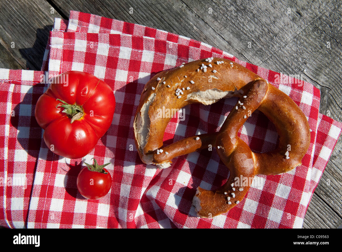 Bretzel et tomates sur des serviettes à carreaux, Bavaria, Germany, Europe Banque D'Images