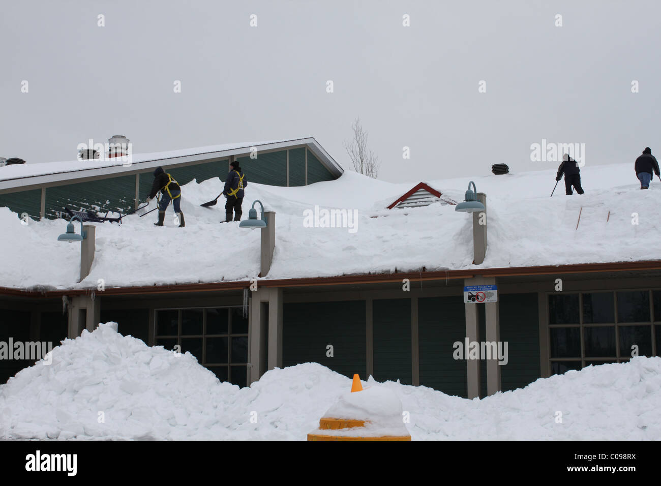 Quatre hommes enlever la neige d'un toit Banque D'Images