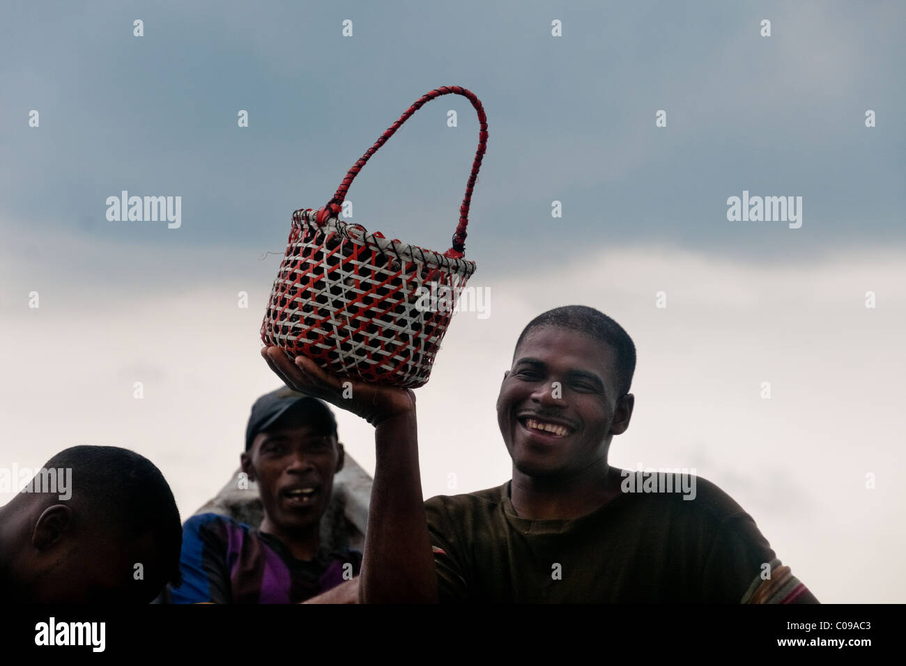 Un homme colombien montre joyeusement un panier plein de coquillages recueillis dans les mangroves de la côte du Pacifique, en Colombie. Banque D'Images