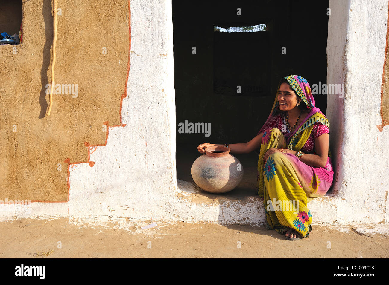 Jeune femme avec cruche d'eau à l'entrée de sa maison, désert de Thar, Rajasthan, Inde, Asie Banque D'Images
