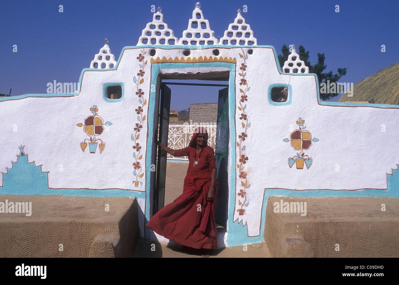 Traditionnellement peints façade d'une maison, une femme portant un sari debout à l'entrée, désert de Thar, Rajasthan, Inde, Asie Banque D'Images