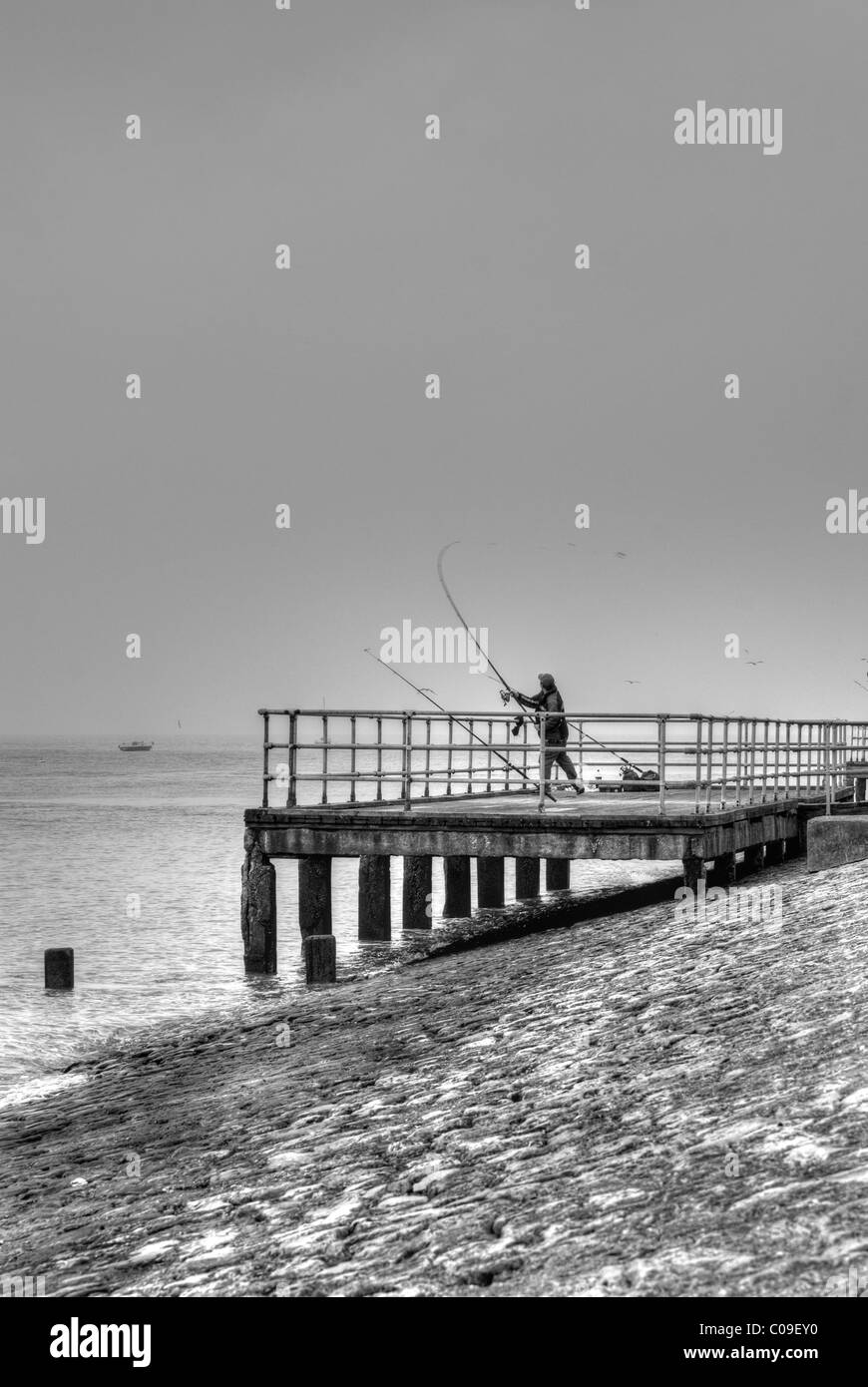 Fisherman casting à partir d'une jetée. Banque D'Images