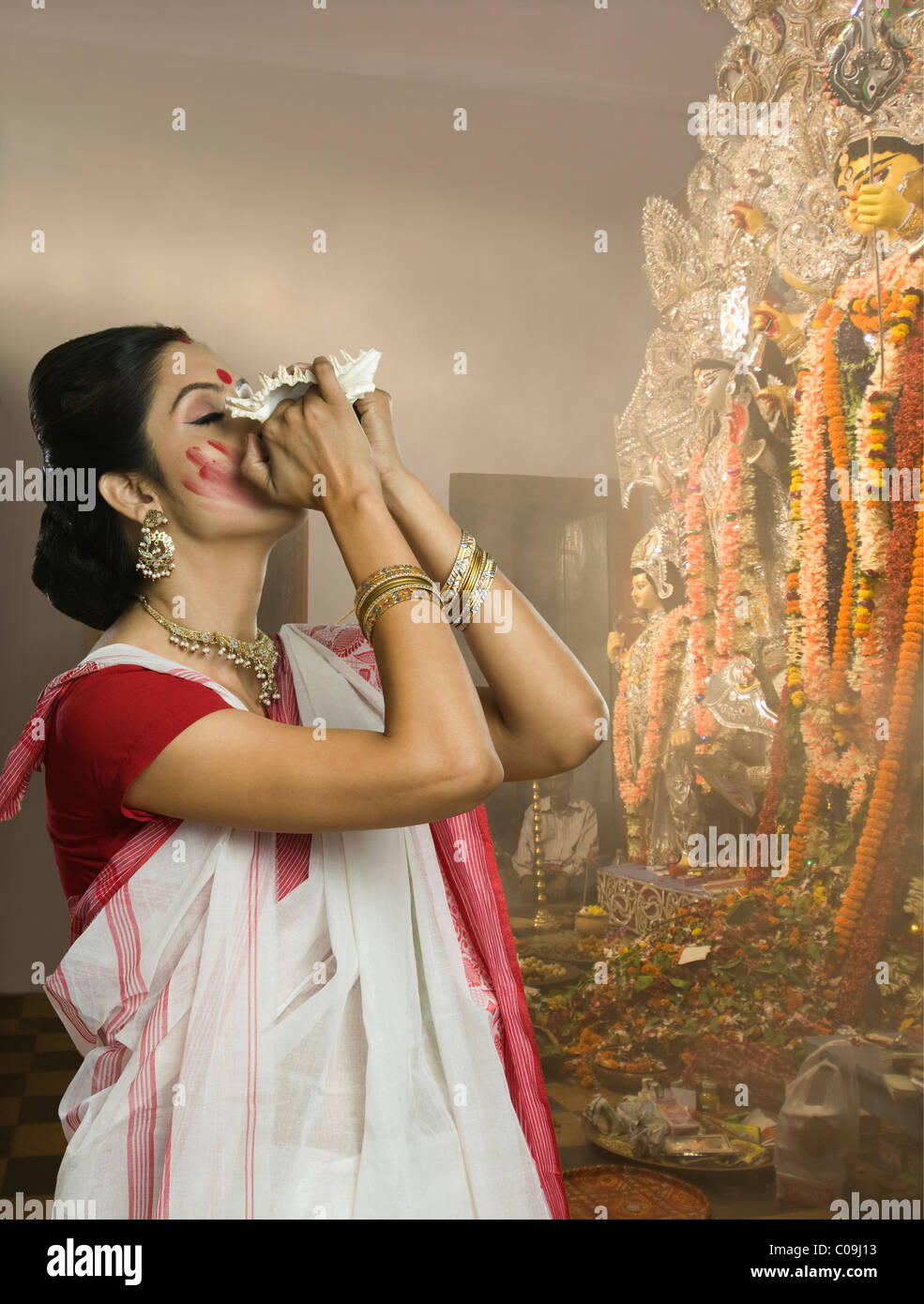 Woman blowing conque à Durga puja Banque D'Images