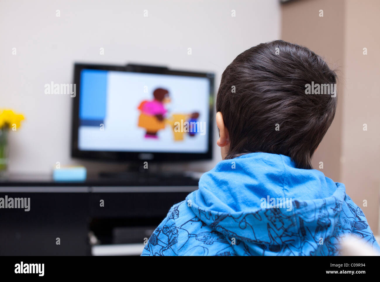 La maison seule-3 ans garçon regarder les dessins animés à la télévision Banque D'Images