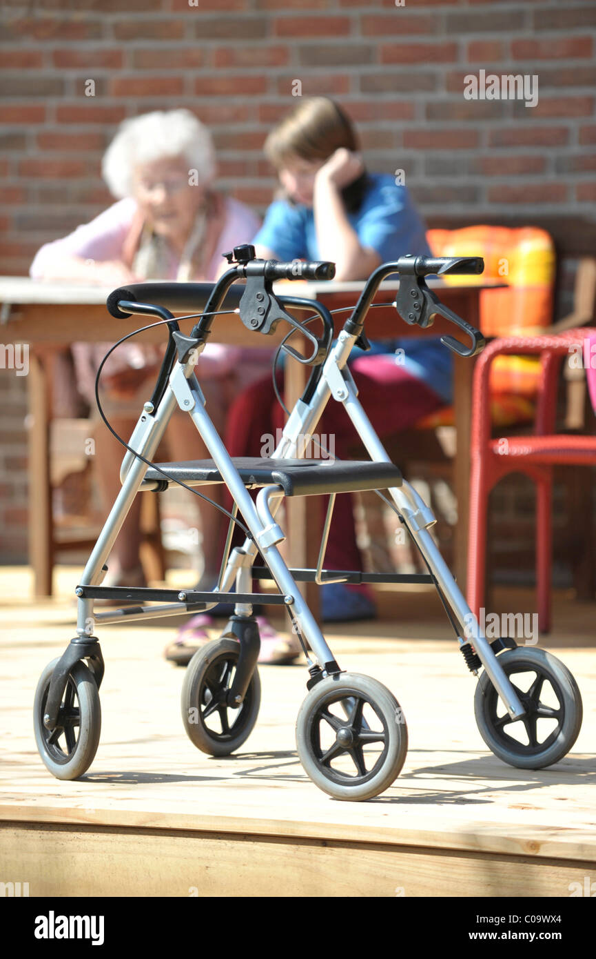 Cadre de marche debout devant une table à laquelle une personne âgée et un étudiant sont assis Banque D'Images
