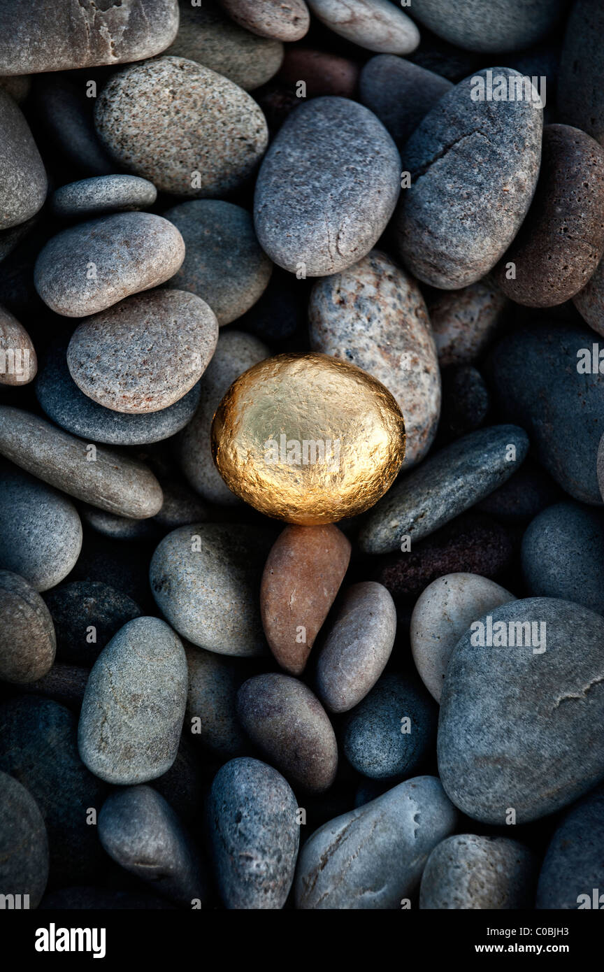Ronde d'or parmi les cailloux galets sur une plage. UK Banque D'Images