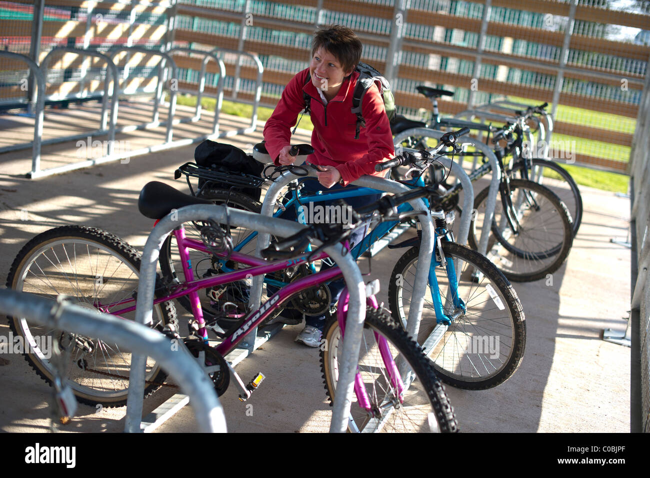 Un cycliste féminin bloque son vélo dans un parc de vélo à l'Université d'Exeter, Devon Banque D'Images