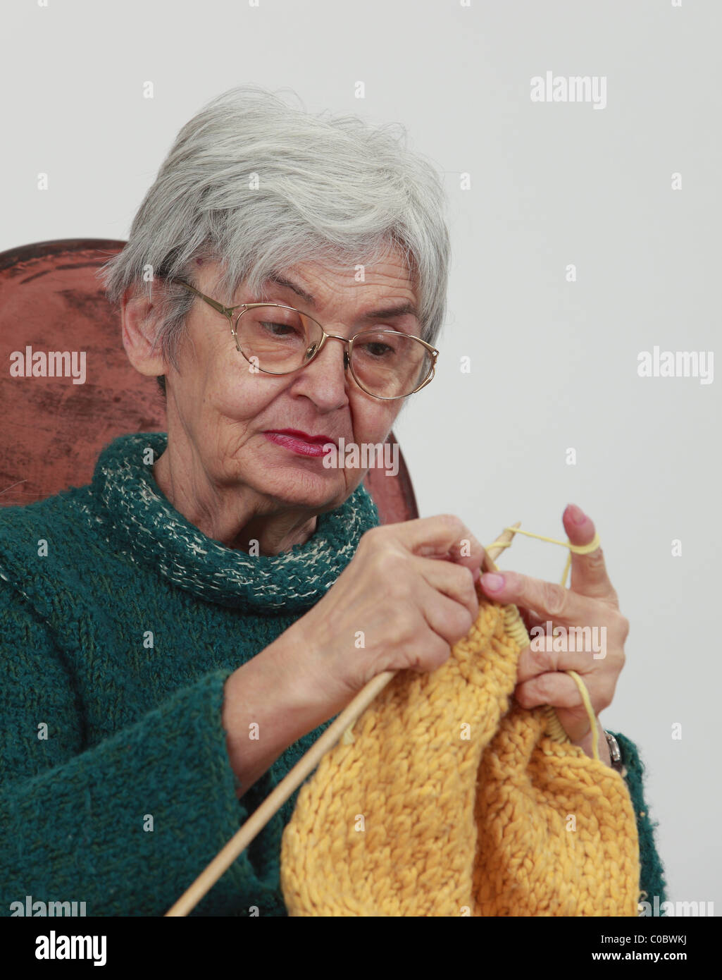 Portrait d'une vieille femme,tricot sur un arrière-plan gris. Banque D'Images