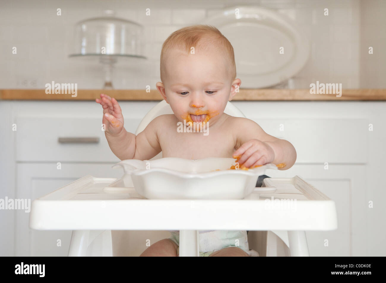 Messy baby eating dans une chaise haute Banque D'Images